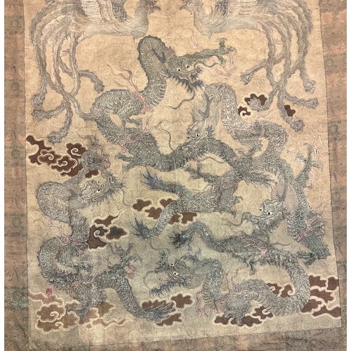 19 - A large antique Chinese silk needlework tapestry wall hanging, decorated with give dragons chasing a... 