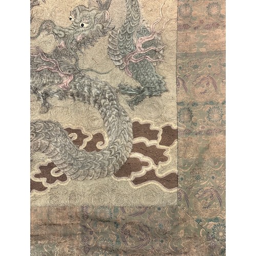 19 - A large antique Chinese silk needlework tapestry wall hanging, decorated with give dragons chasing a... 