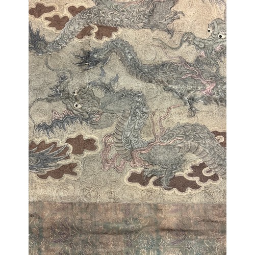 19 - A large antique Chinese silk needlework tapestry wall hanging, decorated with give dragons chasing a... 