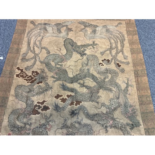 19 - A large antique Chinese silk needlework tapestry wall hanging, decorated with give dragons chasing a... 