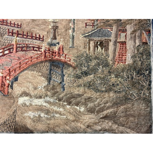 28 - A large Japanese antique silkwork depicting a Japanese town scene with traditional buildings, a red ... 