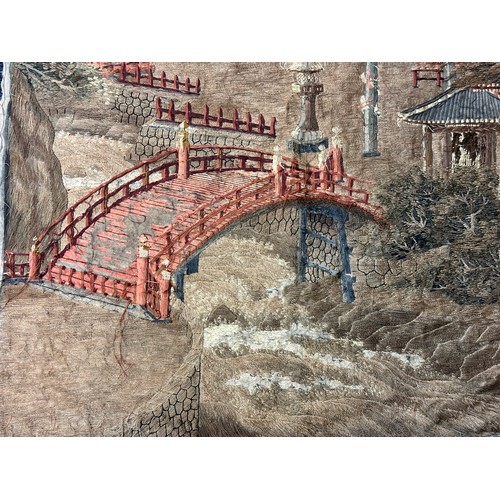 28 - A large Japanese antique silkwork depicting a Japanese town scene with traditional buildings, a red ... 