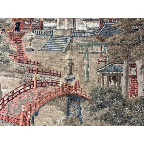 28 - A large Japanese antique silkwork depicting a Japanese town scene with traditional buildings, a red ... 