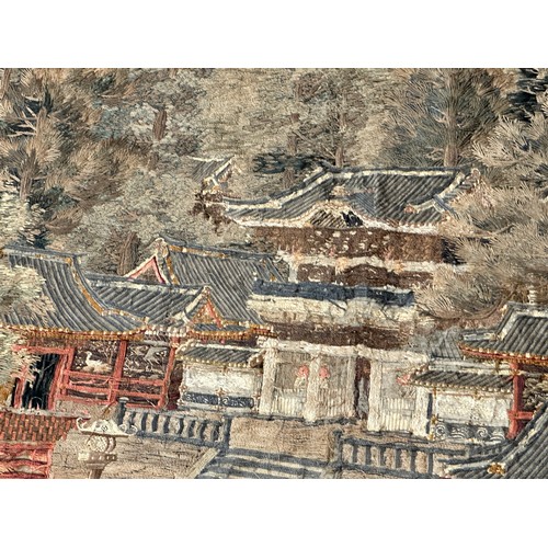 28 - A large Japanese antique silkwork depicting a Japanese town scene with traditional buildings, a red ... 