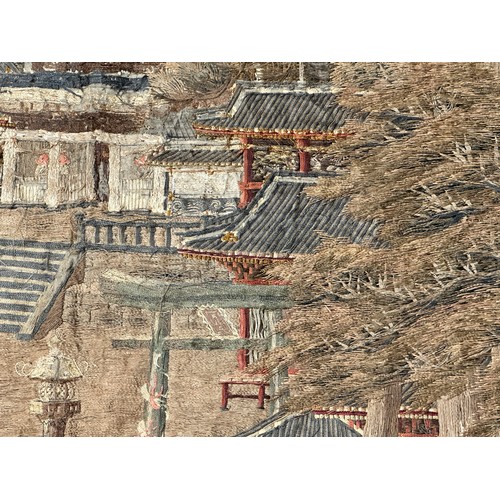 28 - A large Japanese antique silkwork depicting a Japanese town scene with traditional buildings, a red ... 