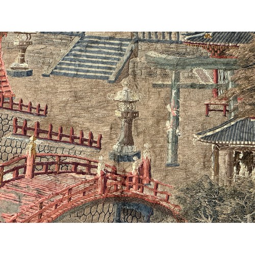 28 - A large Japanese antique silkwork depicting a Japanese town scene with traditional buildings, a red ... 