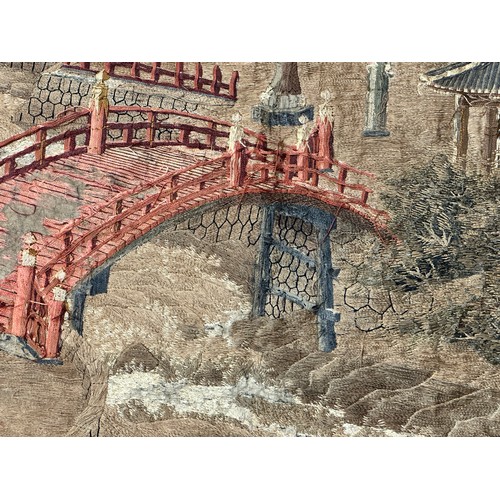 28 - A large Japanese antique silkwork depicting a Japanese town scene with traditional buildings, a red ... 