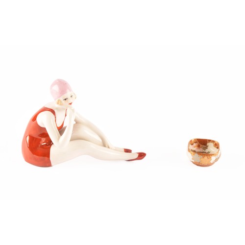 264 - A German Art Deco porcelain figurine of a bathing beauty, 12 x 9 cm, along with a small Japanese dis... 