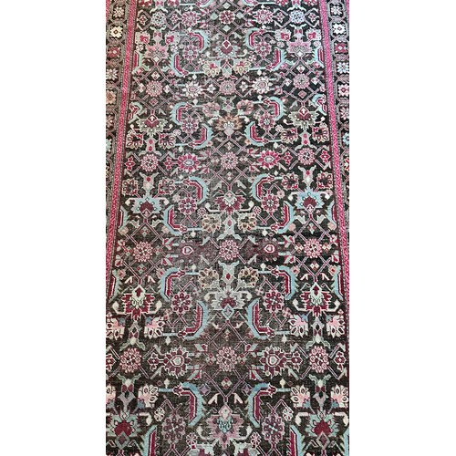 282 - A Persian Heriz handwoven long wool runner featuring geometric floral motifs throughout. The main fi... 