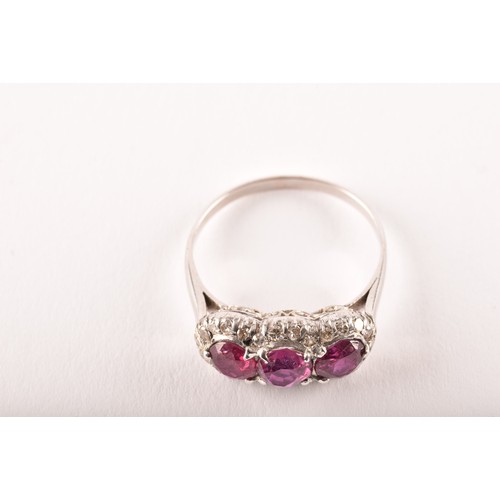 102 - A early 20th century white metal cluster ring, featuring three round old cut rubies with a combined ... 