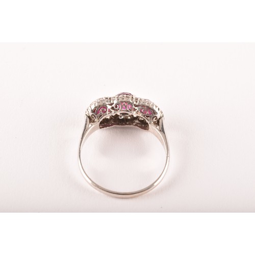 102 - A early 20th century white metal cluster ring, featuring three round old cut rubies with a combined ... 