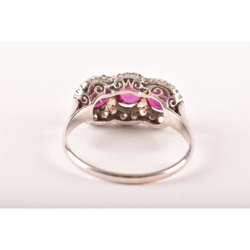 102 - A early 20th century white metal cluster ring, featuring three round old cut rubies with a combined ... 