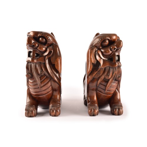 49 - A pair of early 20th century Chinese carved wooden dogs of foe, in a seated pose, with mouths agape.... 