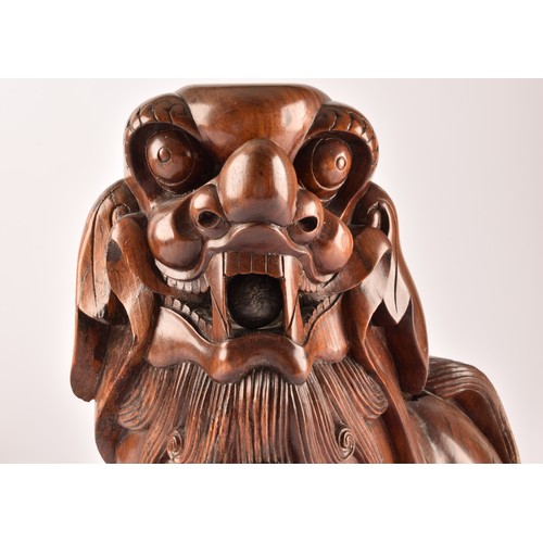 49 - A pair of early 20th century Chinese carved wooden dogs of foe, in a seated pose, with mouths agape.... 