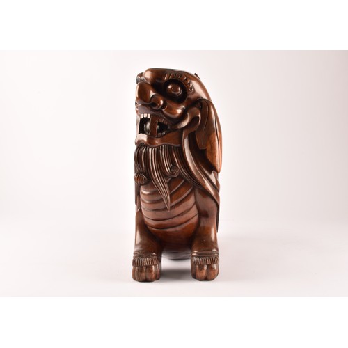 49 - A pair of early 20th century Chinese carved wooden dogs of foe, in a seated pose, with mouths agape.... 