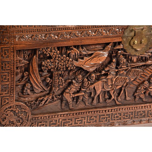 51 - A large Chinese carved camphor wood chest, elaborately carved all over with soldiers and horses trav... 