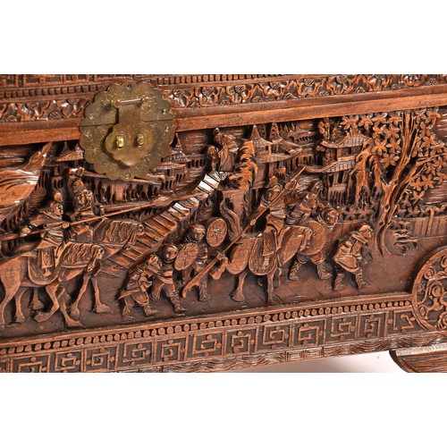 51 - A large Chinese carved camphor wood chest, elaborately carved all over with soldiers and horses trav... 