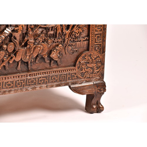 51 - A large Chinese carved camphor wood chest, elaborately carved all over with soldiers and horses trav... 