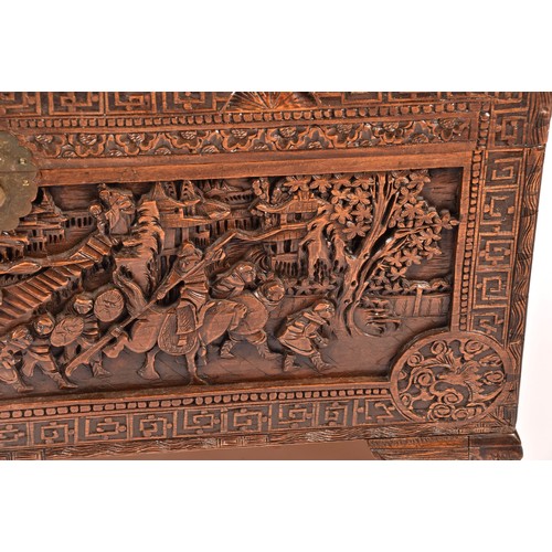 51 - A large Chinese carved camphor wood chest, elaborately carved all over with soldiers and horses trav... 