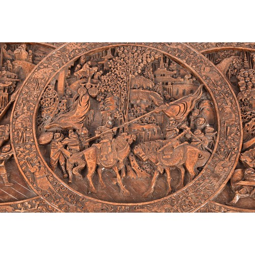 51 - A large Chinese carved camphor wood chest, elaborately carved all over with soldiers and horses trav... 