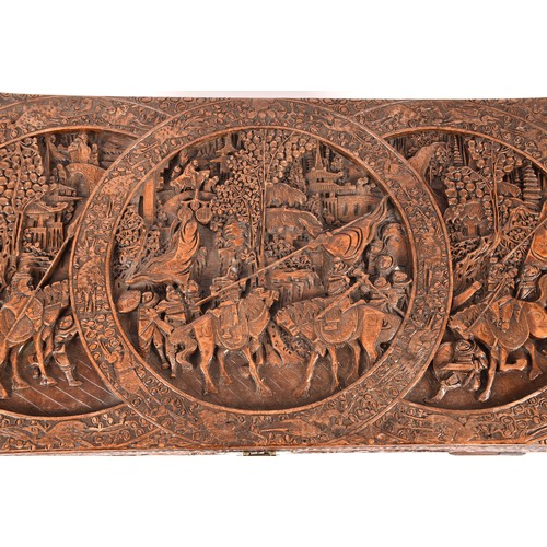 51 - A large Chinese carved camphor wood chest, elaborately carved all over with soldiers and horses trav... 