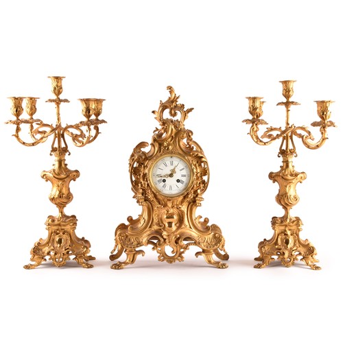 253 - An antique French gilt bronze Rococo style clock garniture, the mantel clock of waisted keyhole shap... 