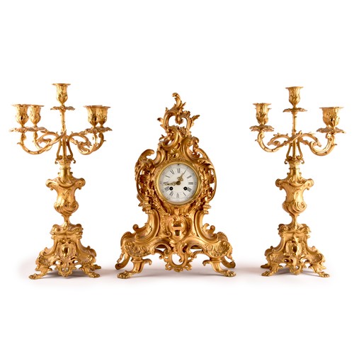 253 - An antique French gilt bronze Rococo style clock garniture, the mantel clock of waisted keyhole shap... 