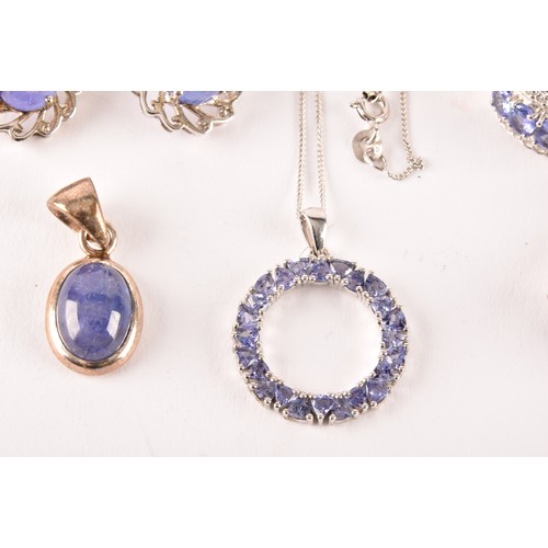 128 - A silver and tanzanite halo pendant on chain, together with a silver and cabochon tanzanite pendant,... 