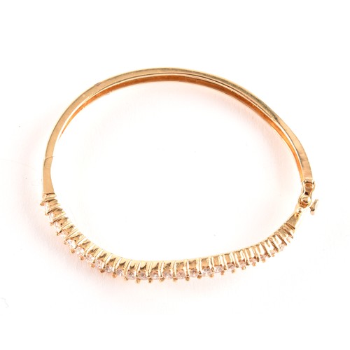 137 - A yellow gold and diamond bangle, of waved design, set with twenty-five round brilliant-cut diamonds... 