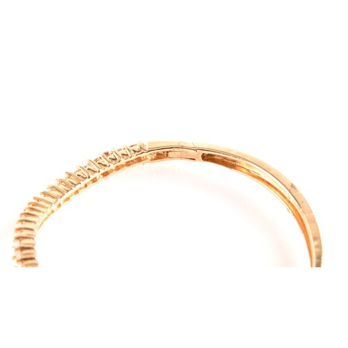 137 - A yellow gold and diamond bangle, of waved design, set with twenty-five round brilliant-cut diamonds... 