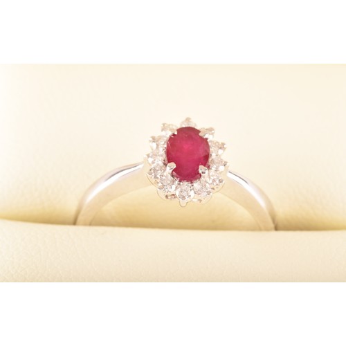 140 - A platinum, diamond, and ruby cluster ring, set with a mixed oval-cut ruby surrounded by round brill... 