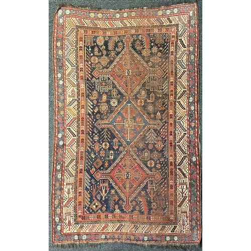 293 - A Persian rug, intricately patterned with shades of deep blues, orange, white and red, fringed edges... 