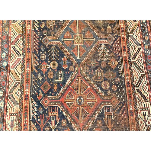 293 - A Persian rug, intricately patterned with shades of deep blues, orange, white and red, fringed edges... 