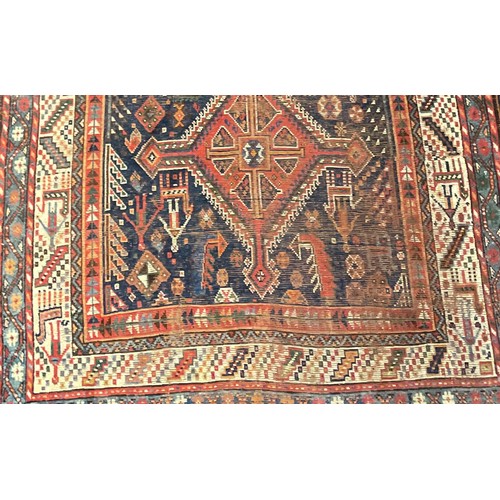 293 - A Persian rug, intricately patterned with shades of deep blues, orange, white and red, fringed edges... 