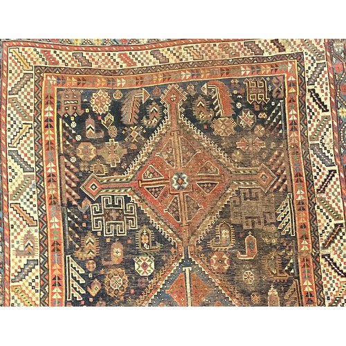 293 - A Persian rug, intricately patterned with shades of deep blues, orange, white and red, fringed edges... 