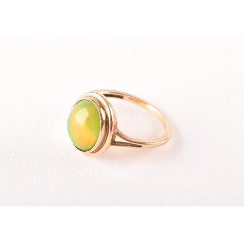 154 - An unusual 9ct yellow gold and opal ring, the oval cabochon opal showing strong green and orange pla... 