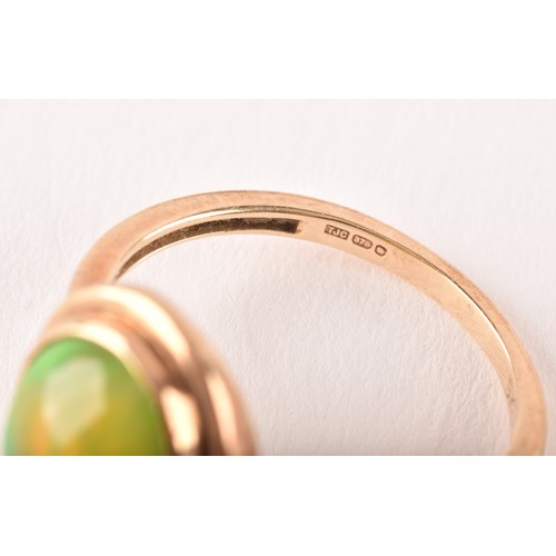 154 - An unusual 9ct yellow gold and opal ring, the oval cabochon opal showing strong green and orange pla... 