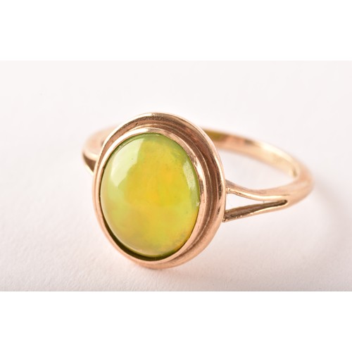 154 - An unusual 9ct yellow gold and opal ring, the oval cabochon opal showing strong green and orange pla... 