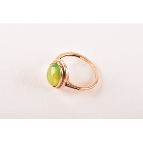 154 - An unusual 9ct yellow gold and opal ring, the oval cabochon opal showing strong green and orange pla... 