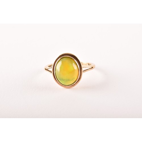 154 - An unusual 9ct yellow gold and opal ring, the oval cabochon opal showing strong green and orange pla... 