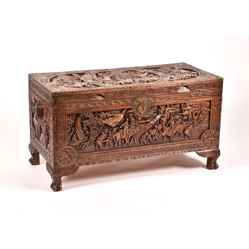 213 - A large Chinese carved camphor wood chest, elaborately carved all over with soldiers and horses trav... 