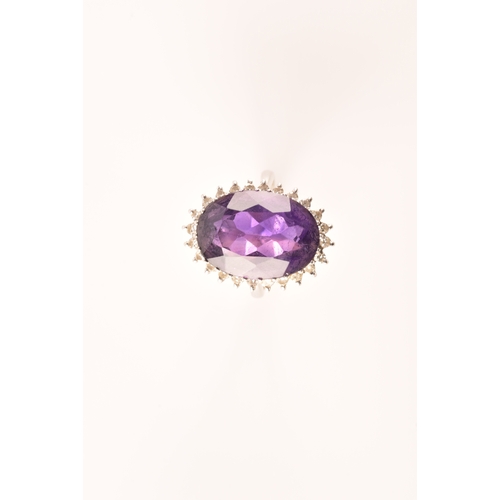 7 - A 18ct white gold amethyst and diamond coronet cluster ring, set to centre with a oval cut amethyst ... 