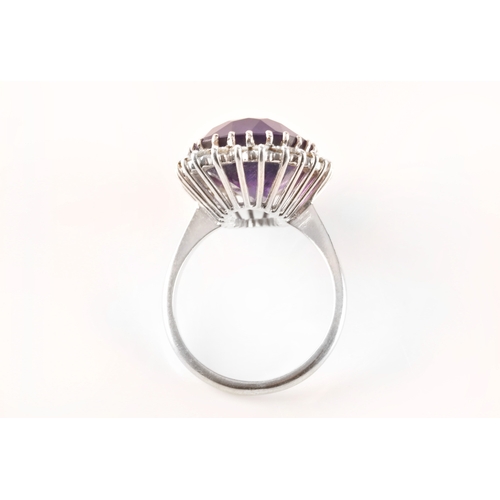 7 - A 18ct white gold amethyst and diamond coronet cluster ring, set to centre with a oval cut amethyst ... 