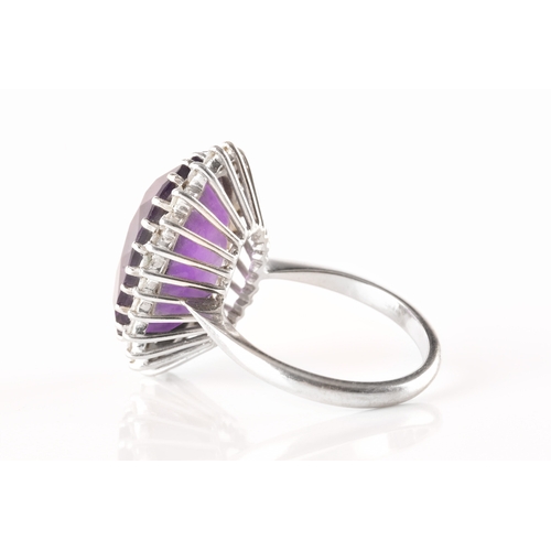 7 - A 18ct white gold amethyst and diamond coronet cluster ring, set to centre with a oval cut amethyst ... 