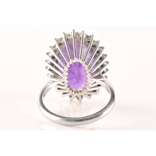 7 - A 18ct white gold amethyst and diamond coronet cluster ring, set to centre with a oval cut amethyst ... 