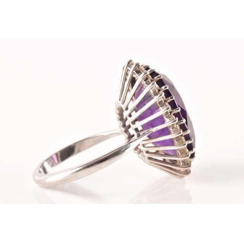 7 - A 18ct white gold amethyst and diamond coronet cluster ring, set to centre with a oval cut amethyst ... 