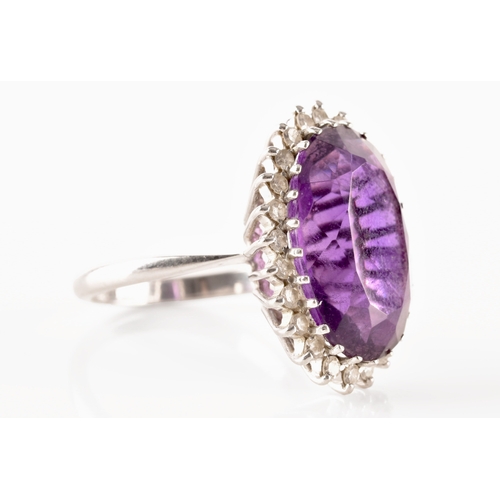 7 - A 18ct white gold amethyst and diamond coronet cluster ring, set to centre with a oval cut amethyst ... 