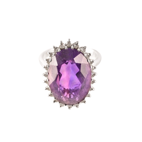 7 - A 18ct white gold amethyst and diamond coronet cluster ring, set to centre with a oval cut amethyst ... 