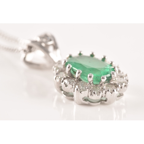 14 - An 18ct white gold emerald and diamond pendant and chain, featuring a oval cut emerald with an appro... 