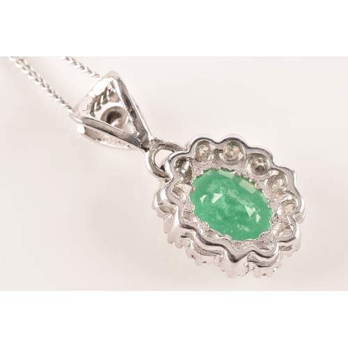 14 - An 18ct white gold emerald and diamond pendant and chain, featuring a oval cut emerald with an appro... 